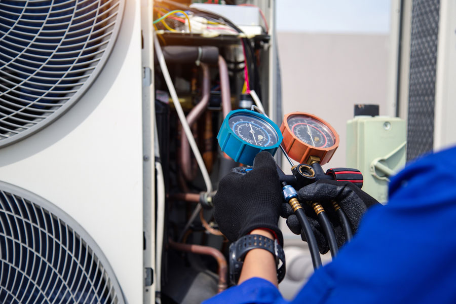 The air conditioner technician is using a gauge to measure the refrigerant pressure