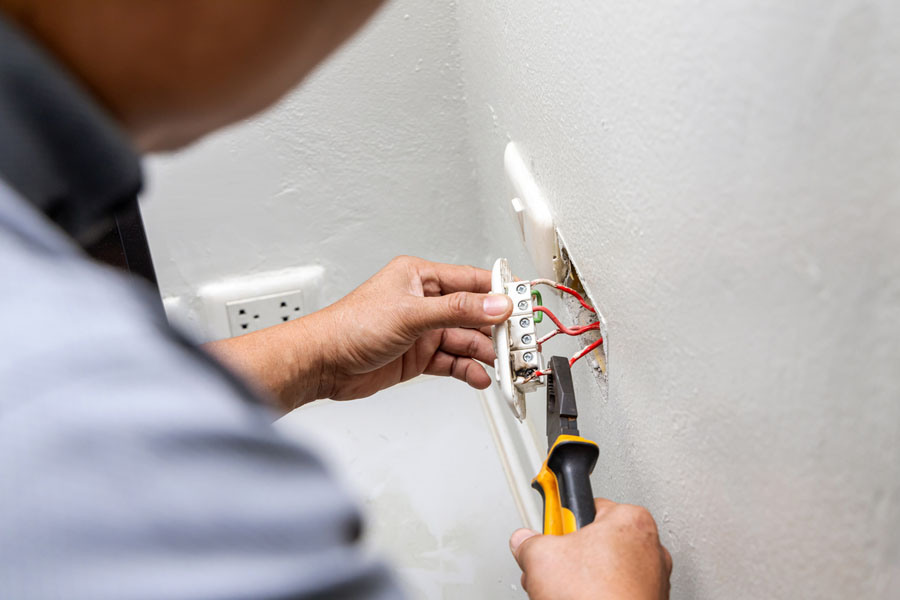 Electrician holding electric outlet plug for repair or maintenance and fixing in office room.