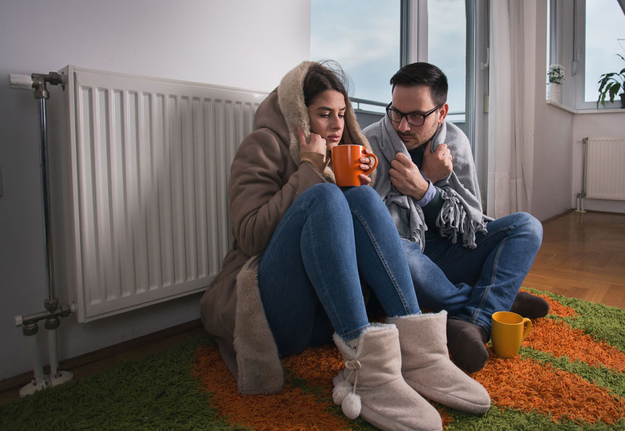 Young couple in jacket and covered with blanket sitting on floor
