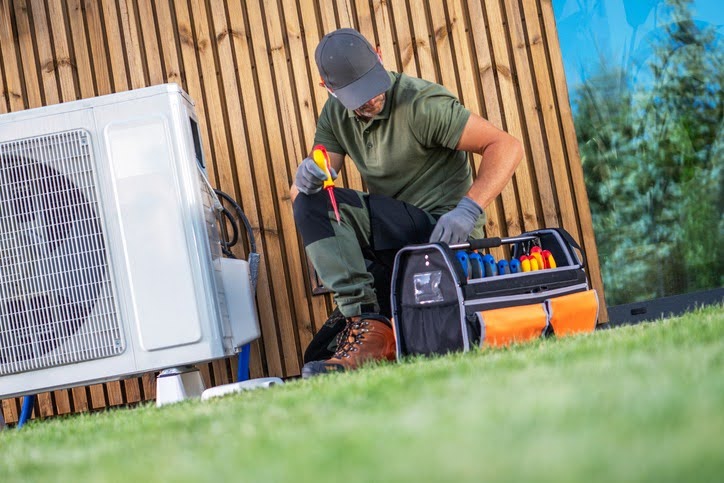 HVAC technician working on an outdoor condenser unit in the summer